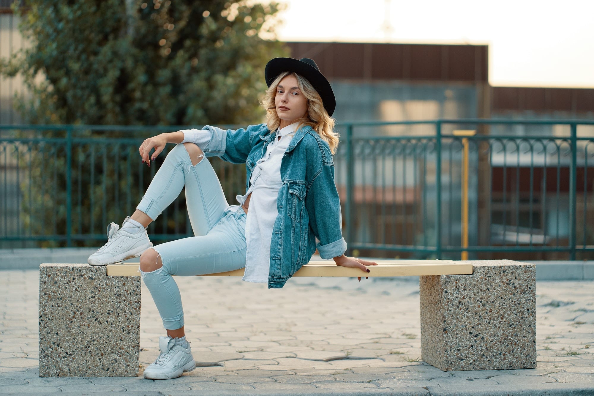 A modern, stylish girl posing while sitting on a minimal city be