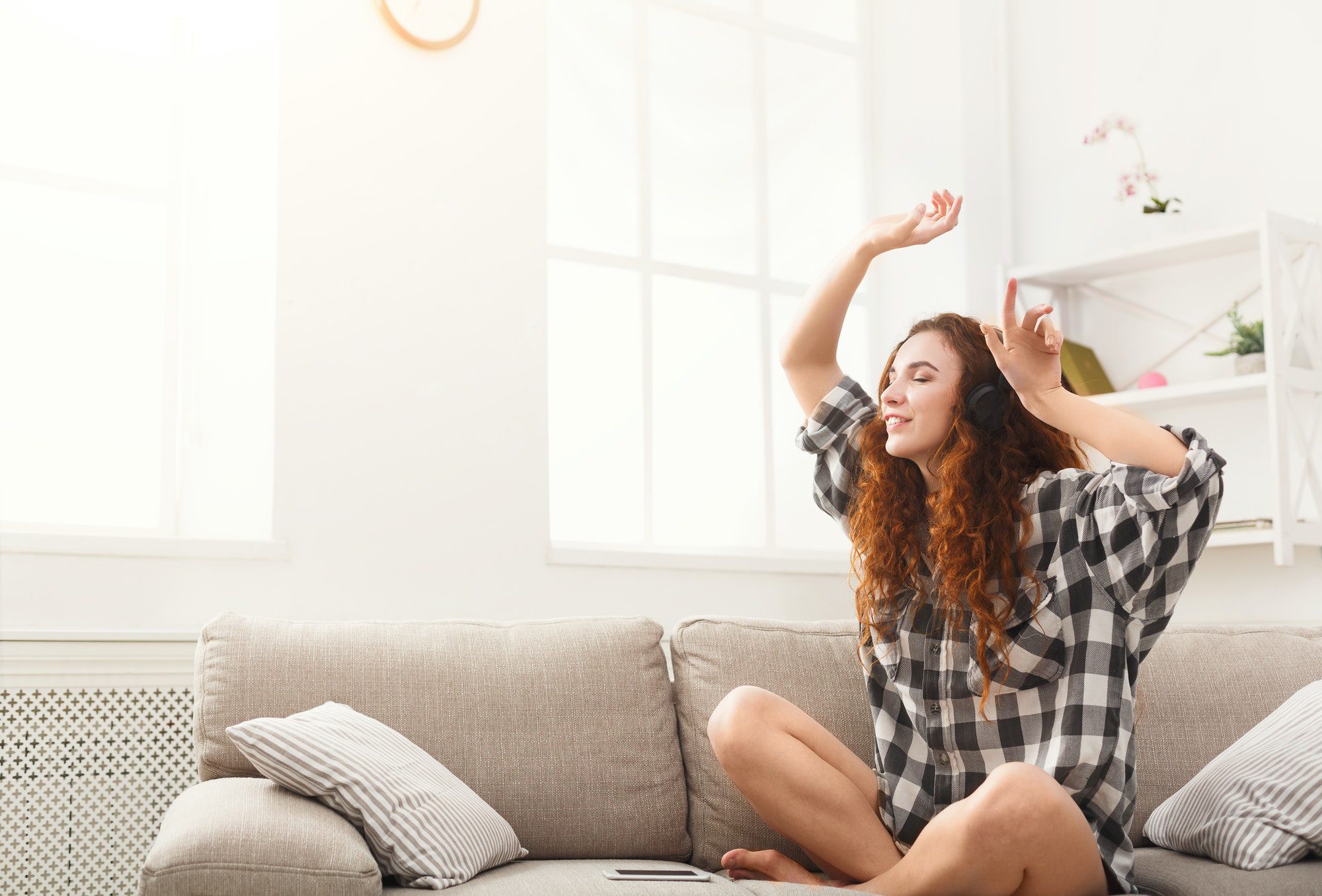 Happy woman in headphones on the couch