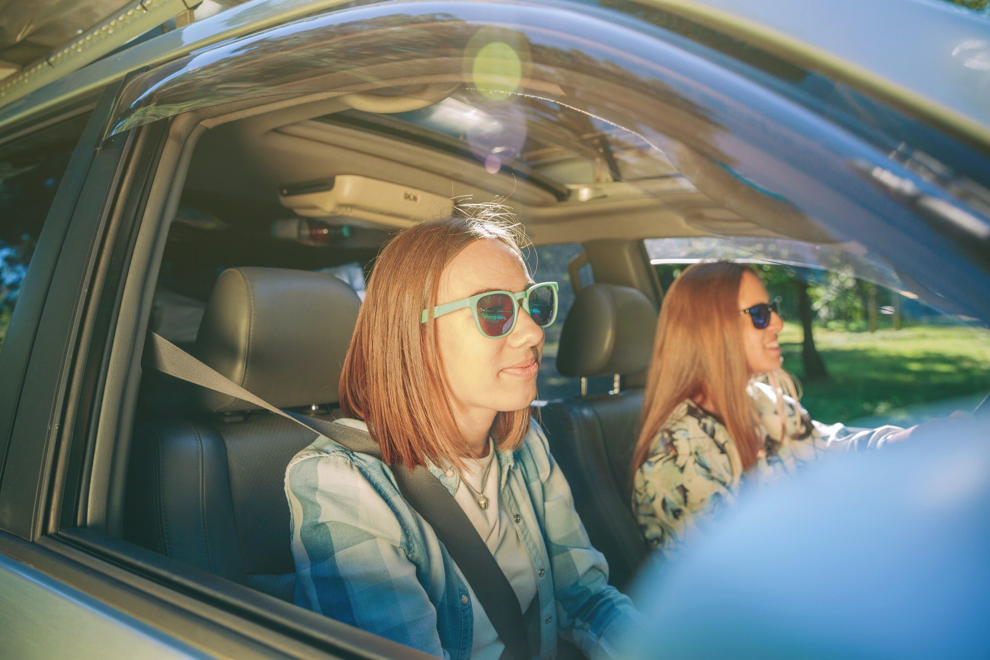 Two happy young women traveling in car