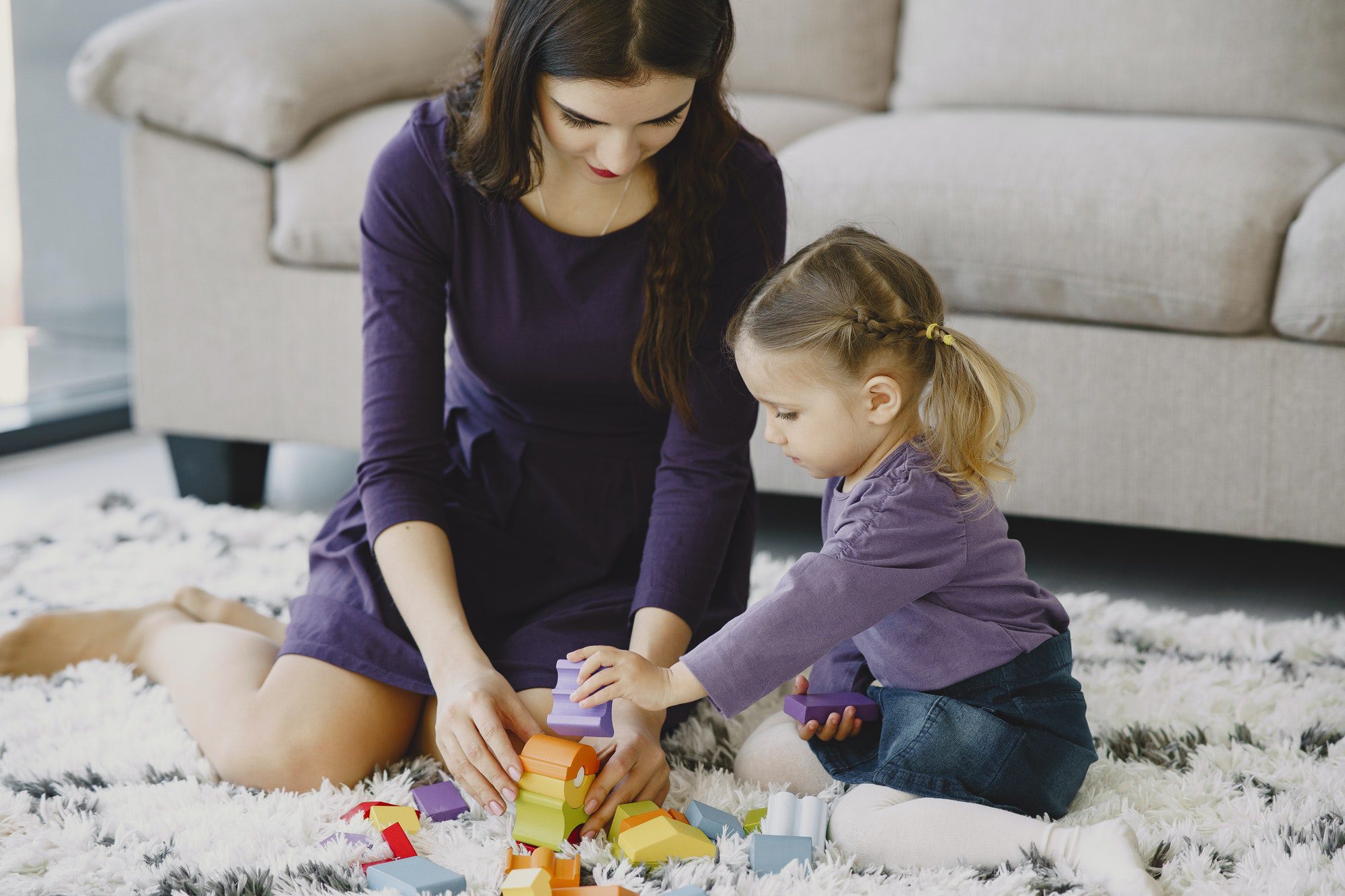 Cheerful mom playing laughing with little kid daughter