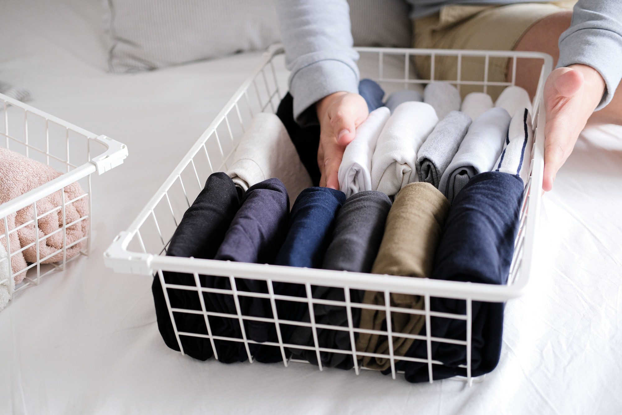 Closeup of hands of an man tidy up things in mesh storage containers. Vertical storage of clothing.