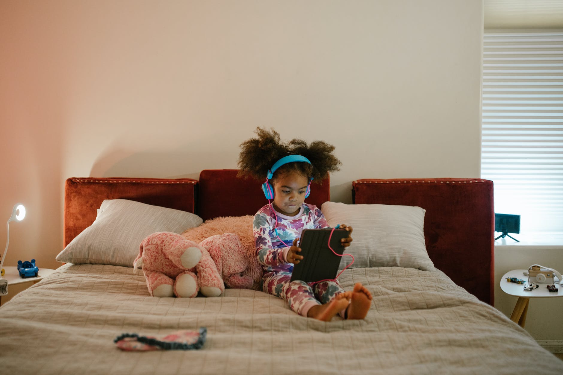 little girl using tablet in bed