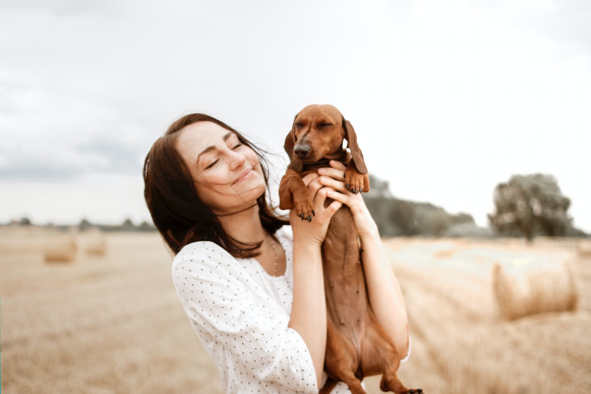 smiling woman carrying brown dachshund