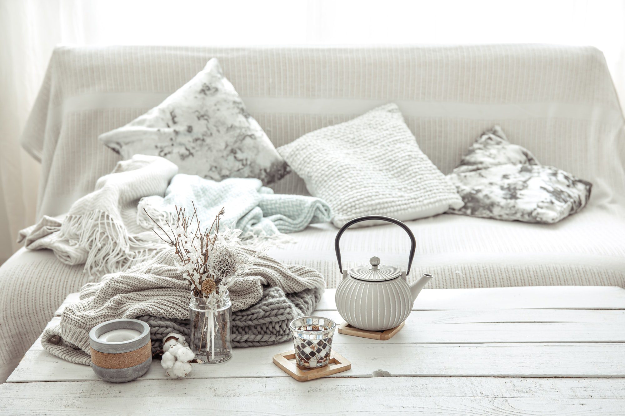 A teapot with details of hygge decor on the table in the living room.