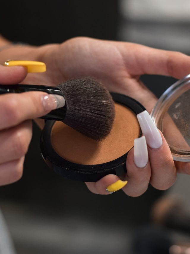 Young woman, teenage girl is using make up brush to apply bronzer, getting ready to go out