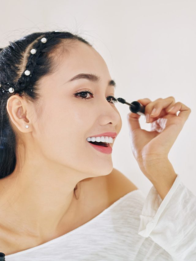 Young woman applying mascara