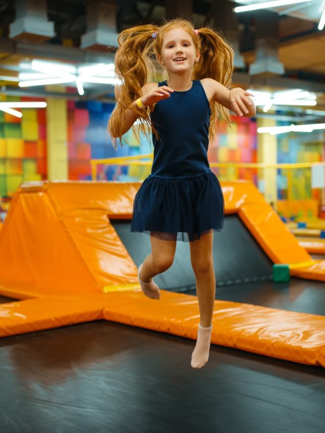 Adorable little girl bouncing on kids trampoline