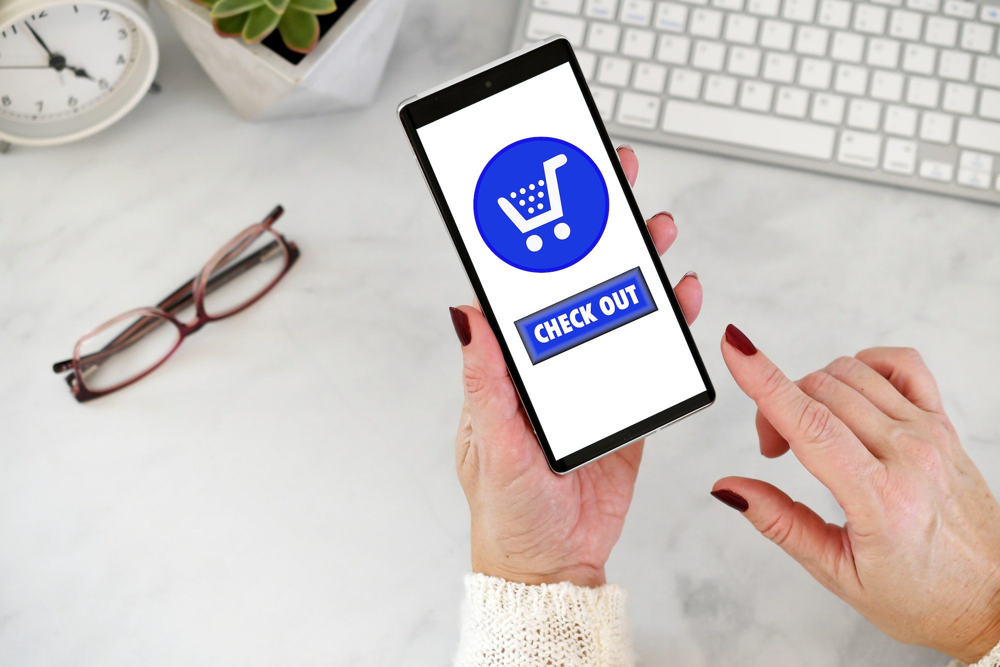 Female using cell phone to shop online - blue shopping cart with checkout check out button