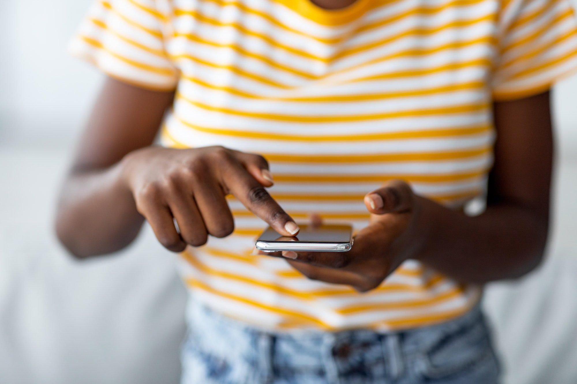 Unrecognizable black woman using brand new mobile phone