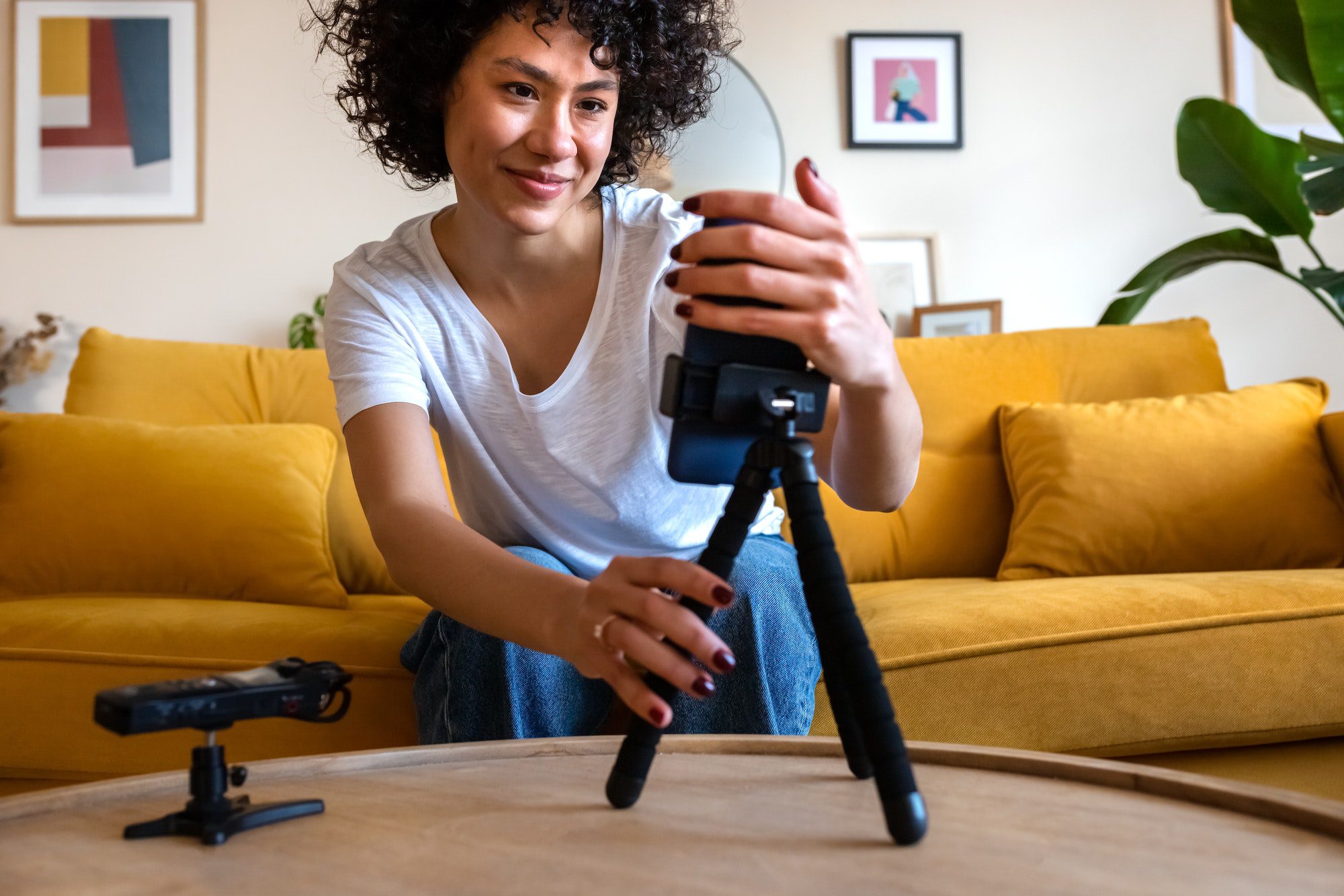 African American vlogger woman setting u phone and voice recorder to film video for social media.