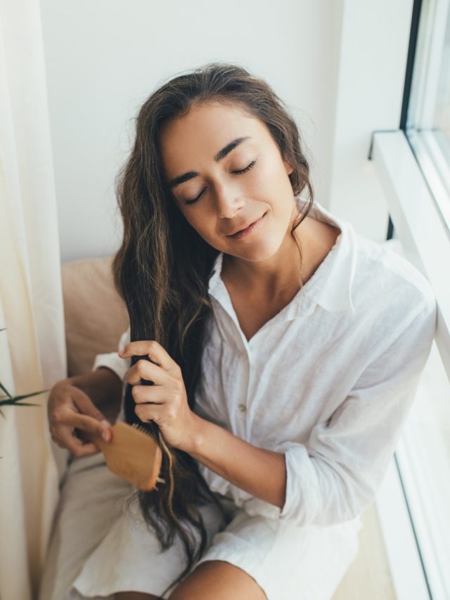 Woman brushing her long healthy hair. Home spa beauty rituals.