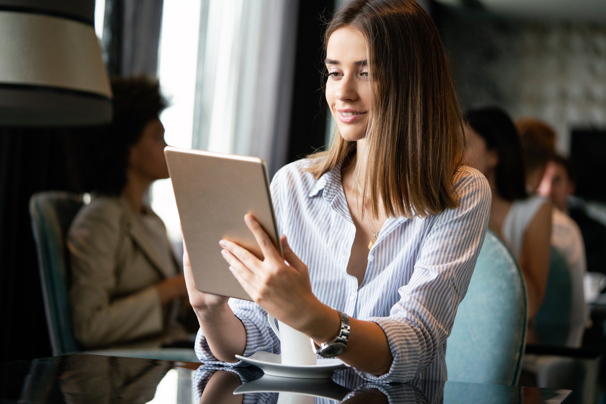 Young professional businesswoman sitting at table at cafe