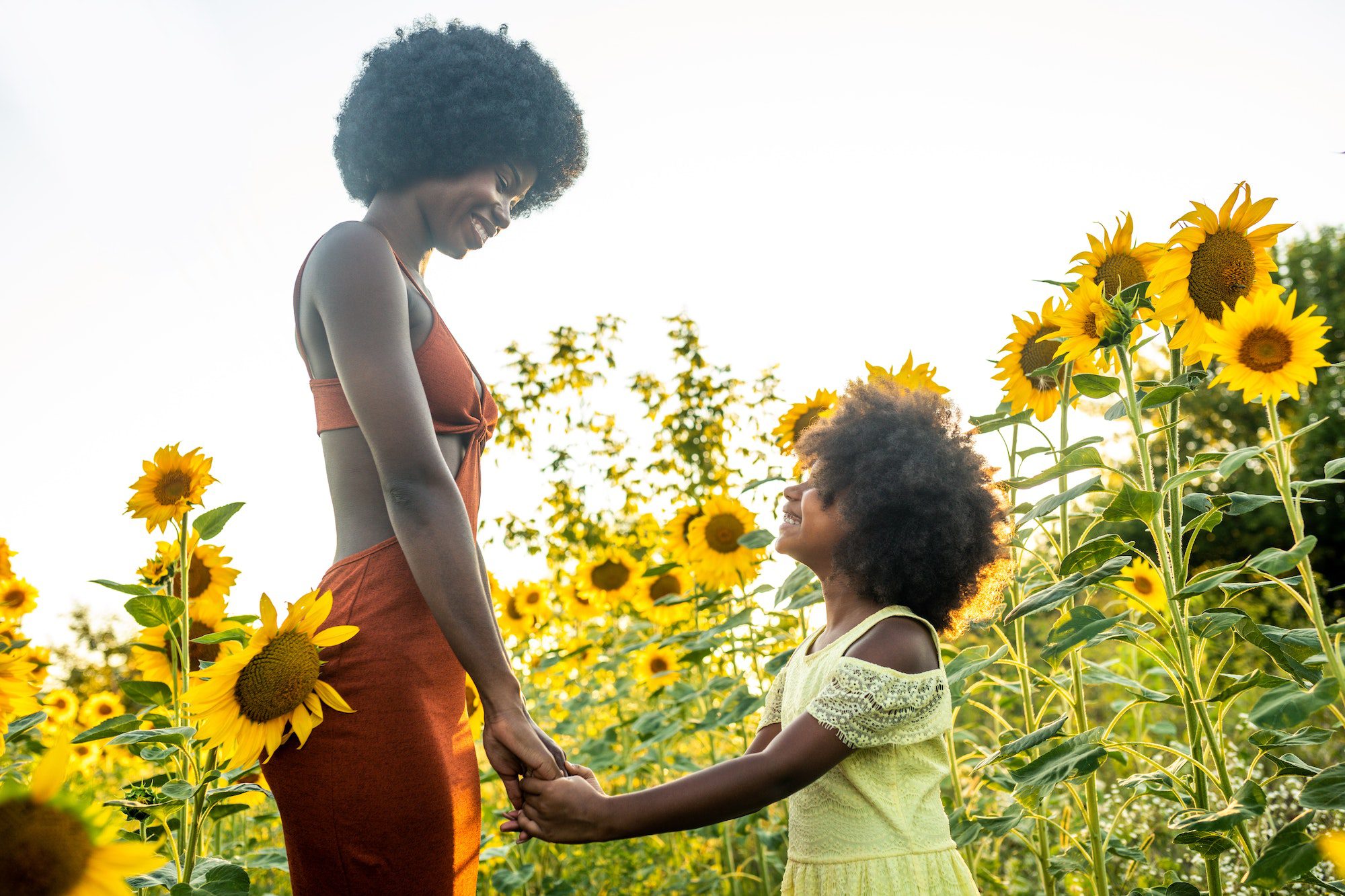 Beautiful mom and daughter in a sunflowers field