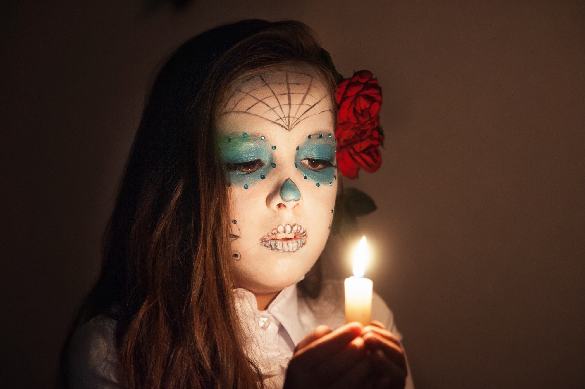 Girl with Halloween make up holding a burning candle.