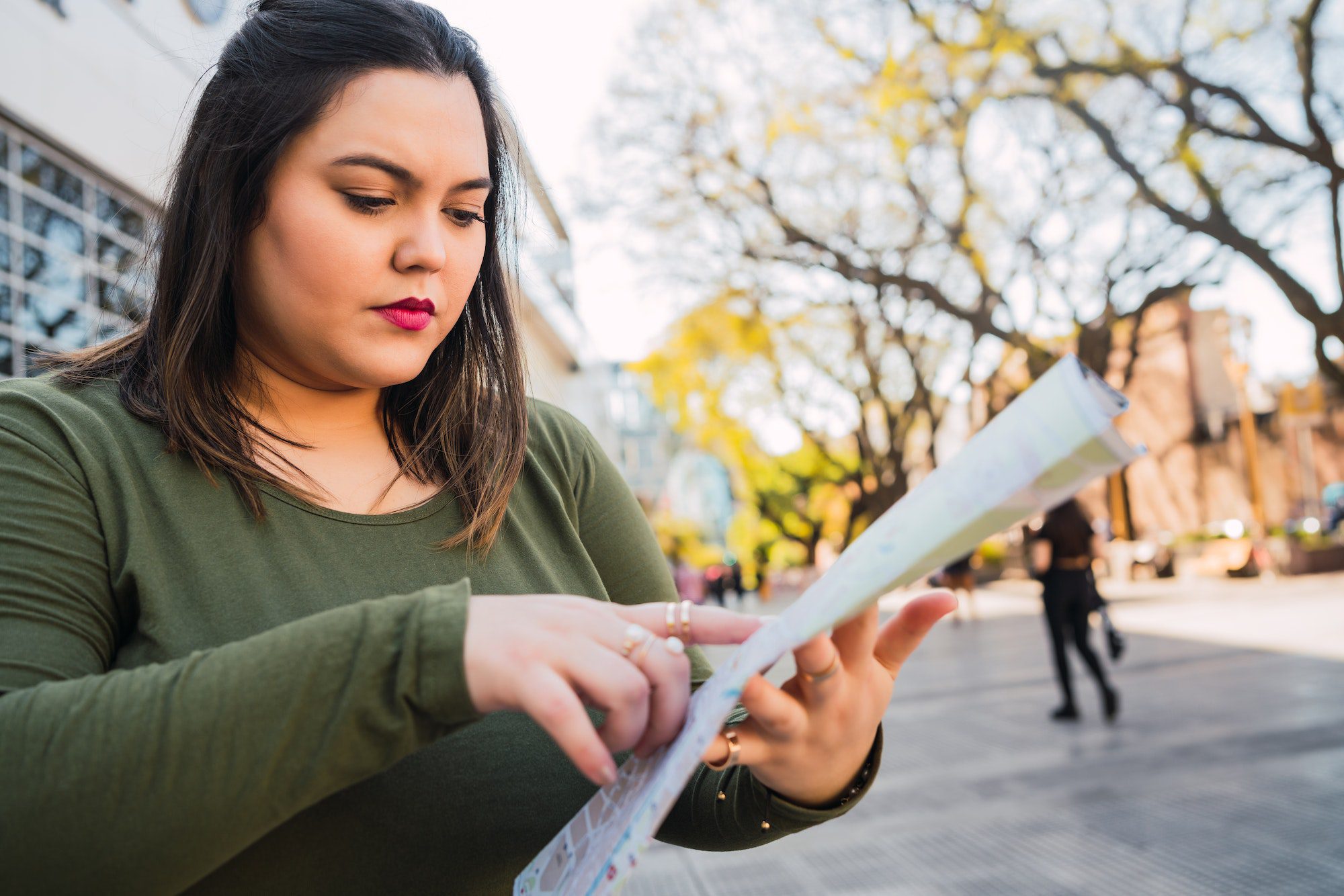 Young woman holding a map and looking for directions.