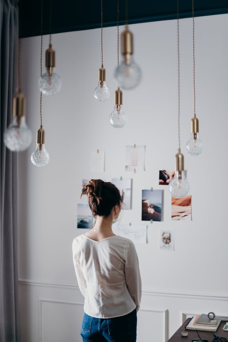 woman under pendant lights looking at the photo on the wall