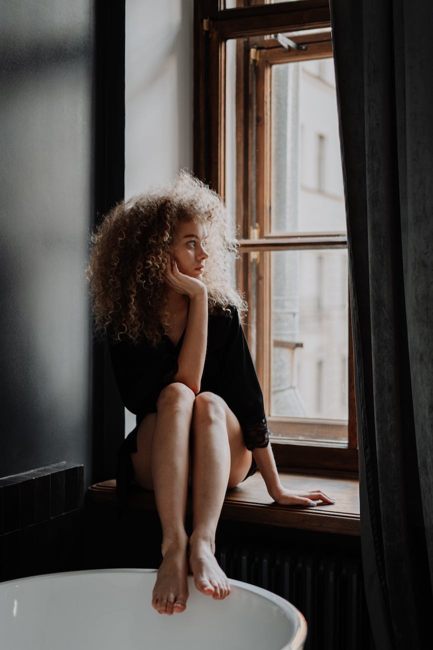 woman in black tank top sitting on window