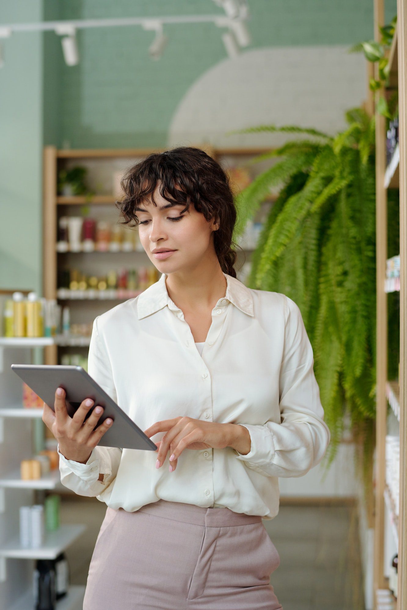 Young confident businesswoman with tablet checking prices of self care products