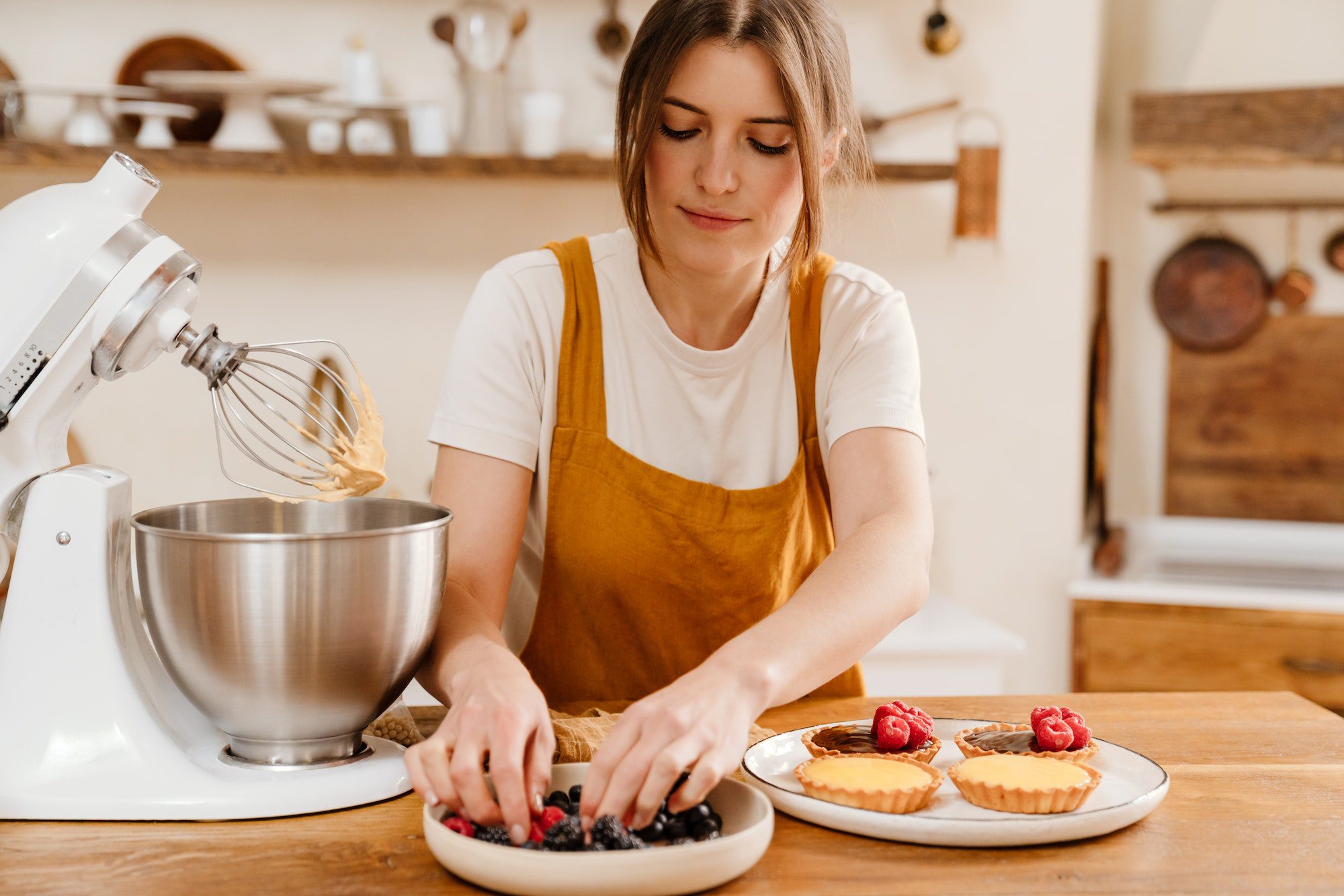 Beautiful concentrated pastry chef woman making tarts with berries