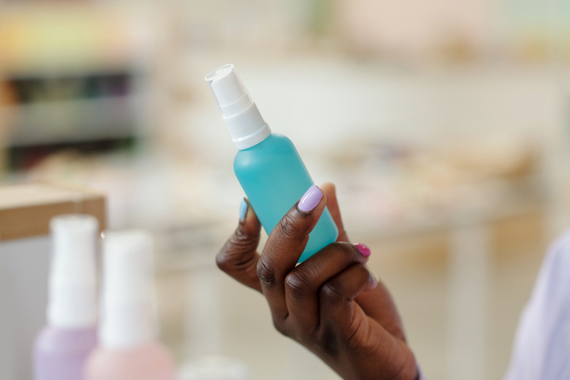 Hand of black girl holding bottle with liquid for fast drying of nail lacquer