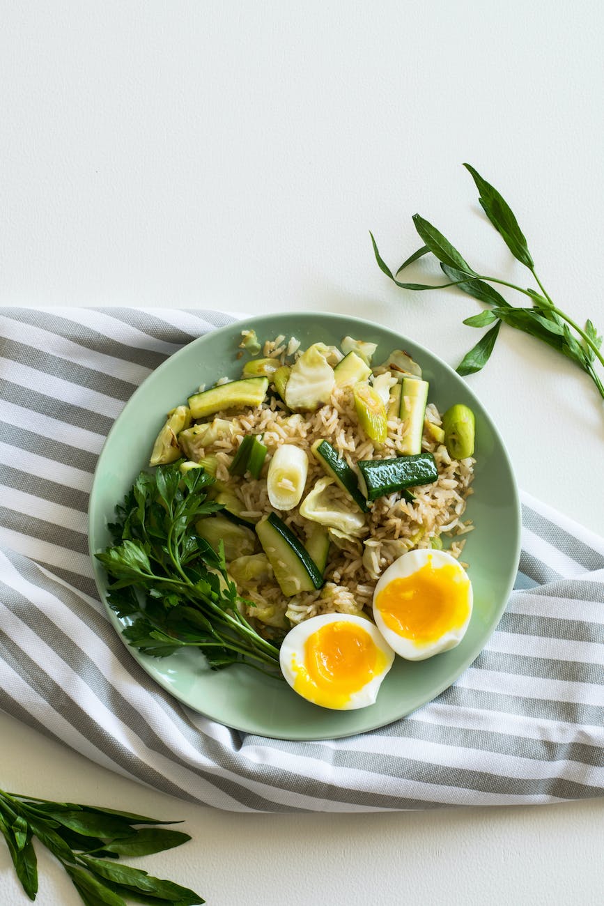 rice with zucchini soft boiled egg and parsley in green ceramic plate