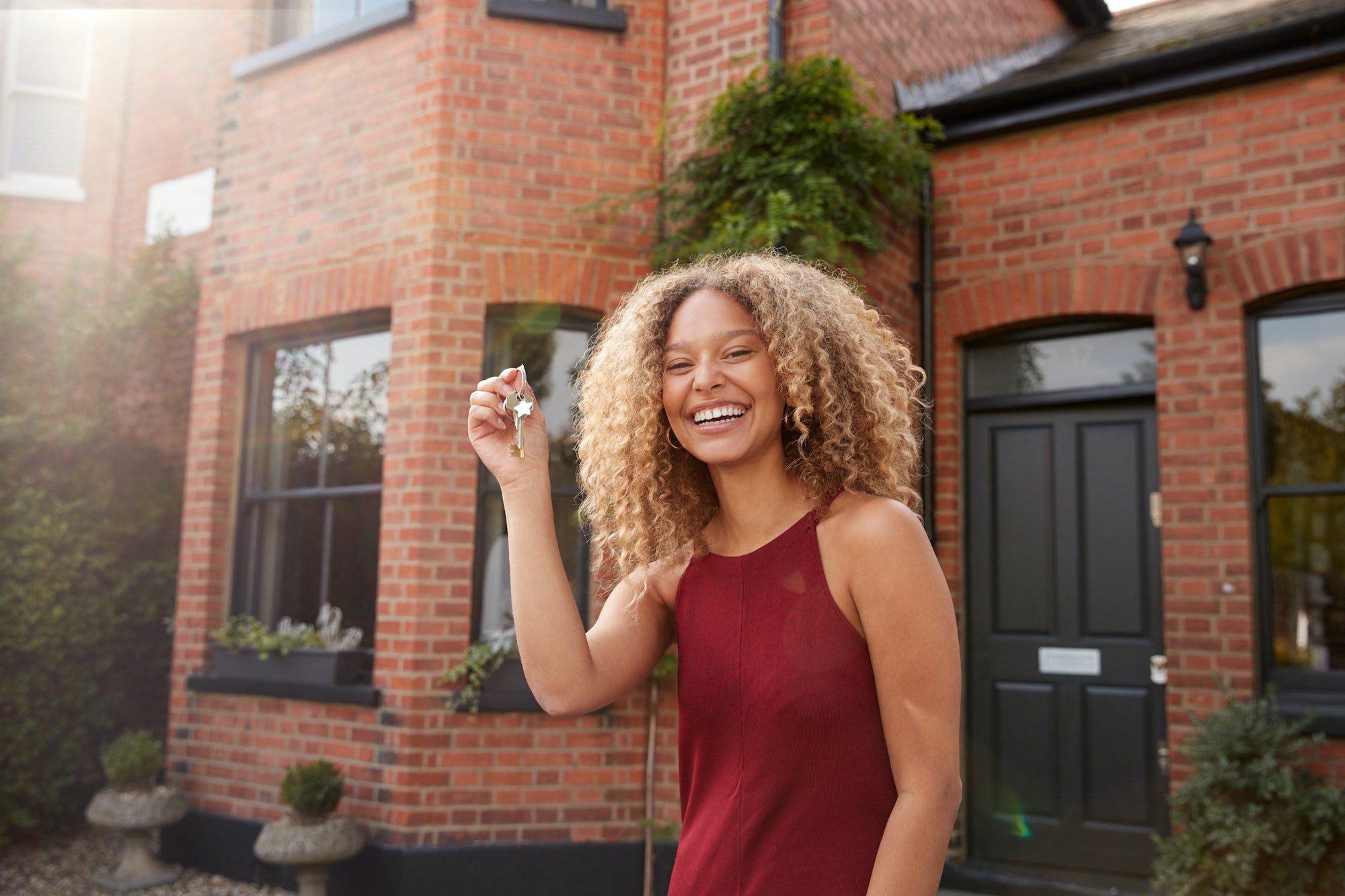 Portrait Of Excited Young Woman Standing Outside New Home Holding Keys