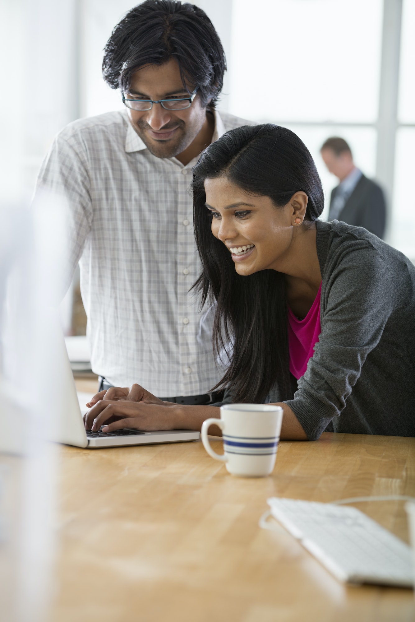 A business environment, an office workplace. A man and a woman using a laptop computer.