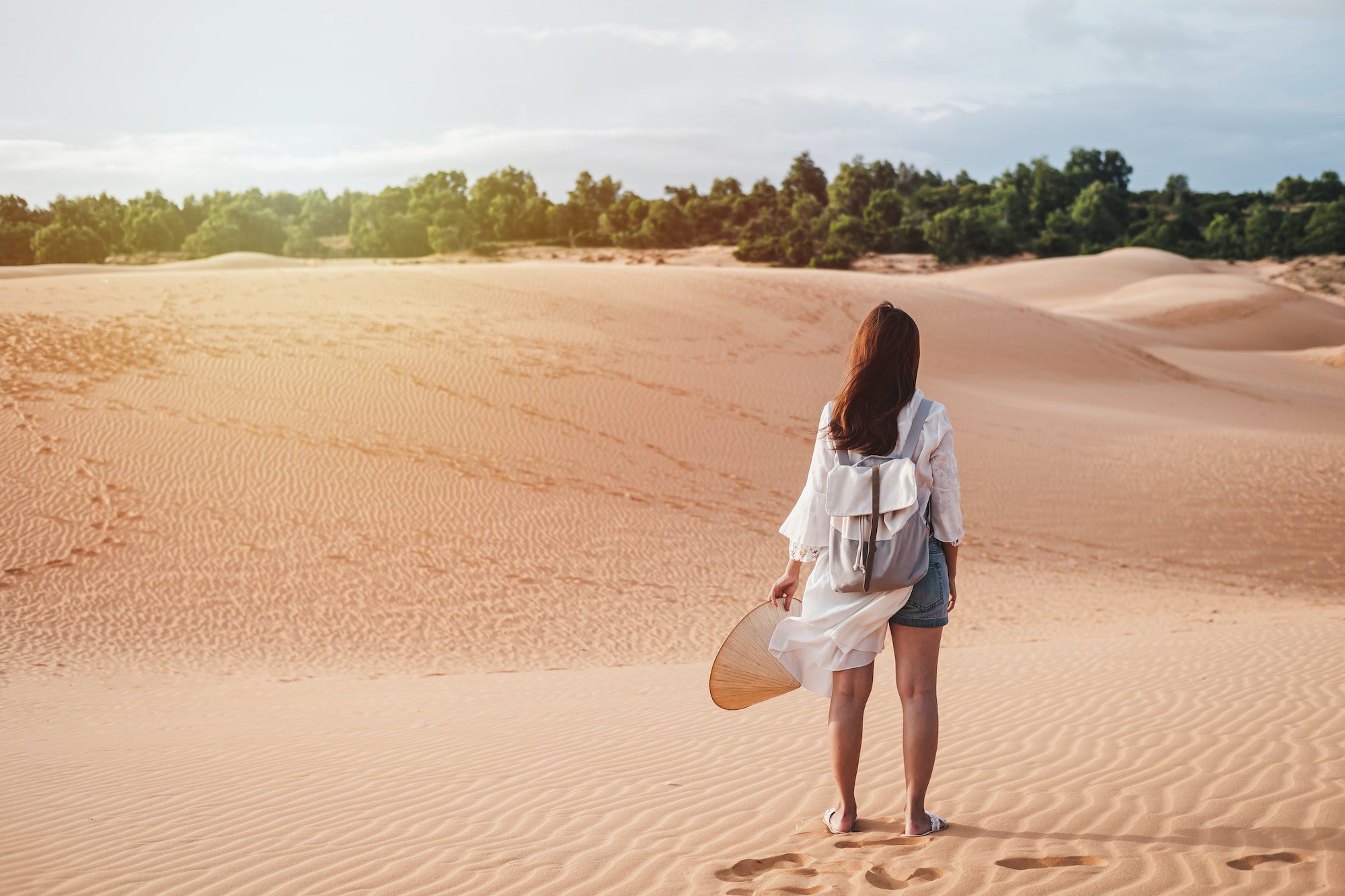 Young woman traveler walking at red sand dunes in Vietnam, Travel lifestyle concept